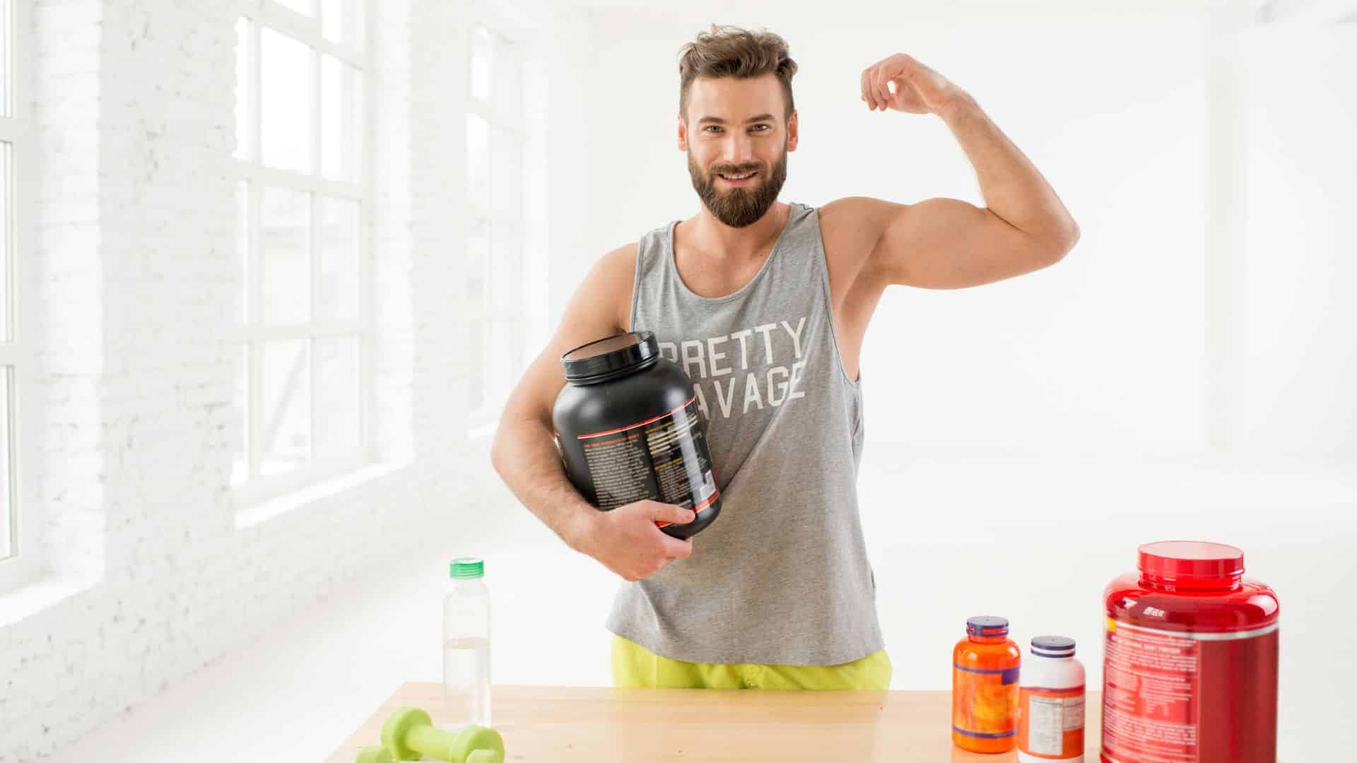 homem mostrando o braço forte e segurando um pote de whey protein